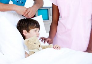 ילד במיטת טיפולים מחבק דובי