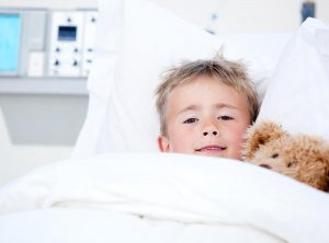 ילד שוכב במיטת טיפולים ומחבק דובון