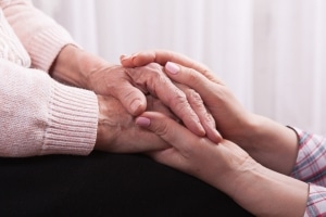 ידיים של אשה צעירה אוחזות בידיים של אשה מבוגרת